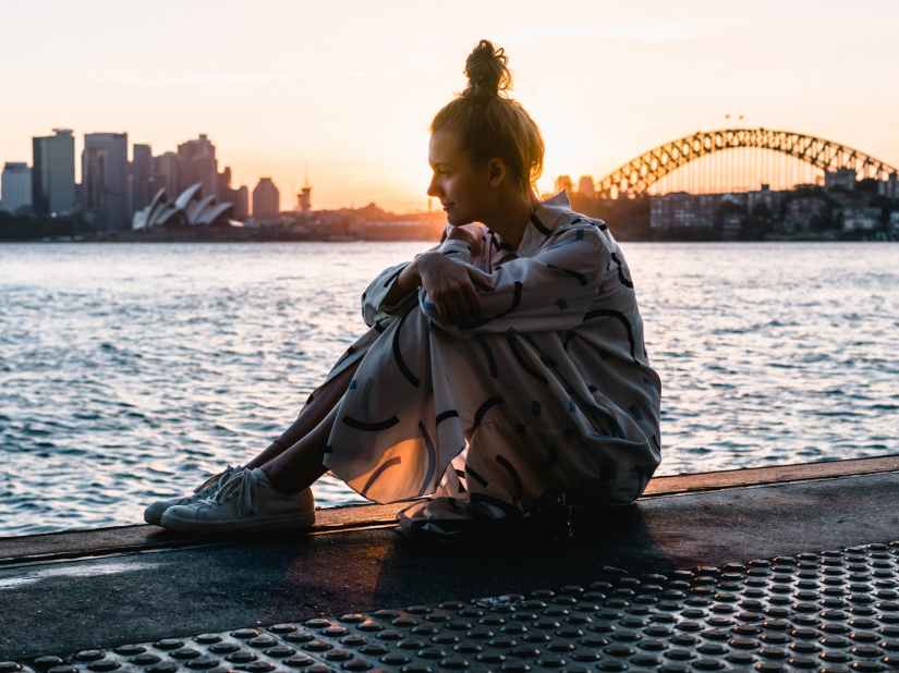 woman sitting on floor near body of water